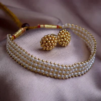 A pearl and gold bead choker with matching earrings on a soft pink fabric. The jewelry's elegance and intricate design evoke a sense of luxury.
